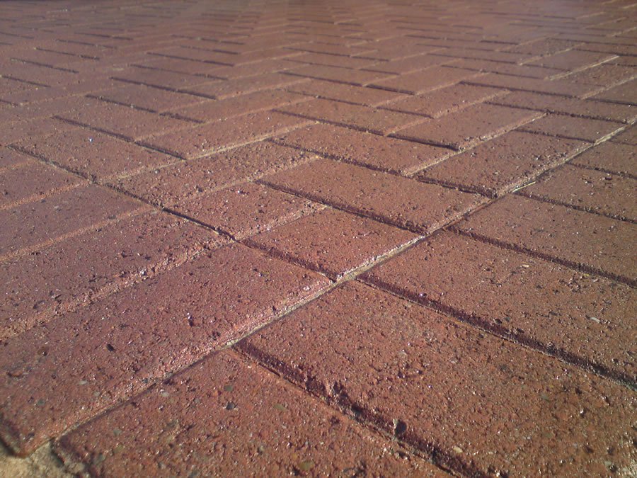 Red block-paved driveway with interlocking bricks and visible surface dirt